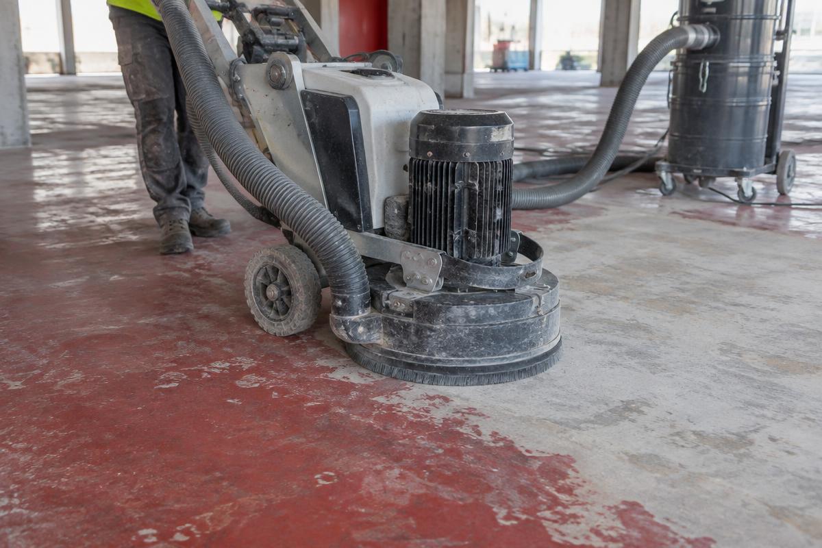 Floor grinder removing old paint from a concrete slab