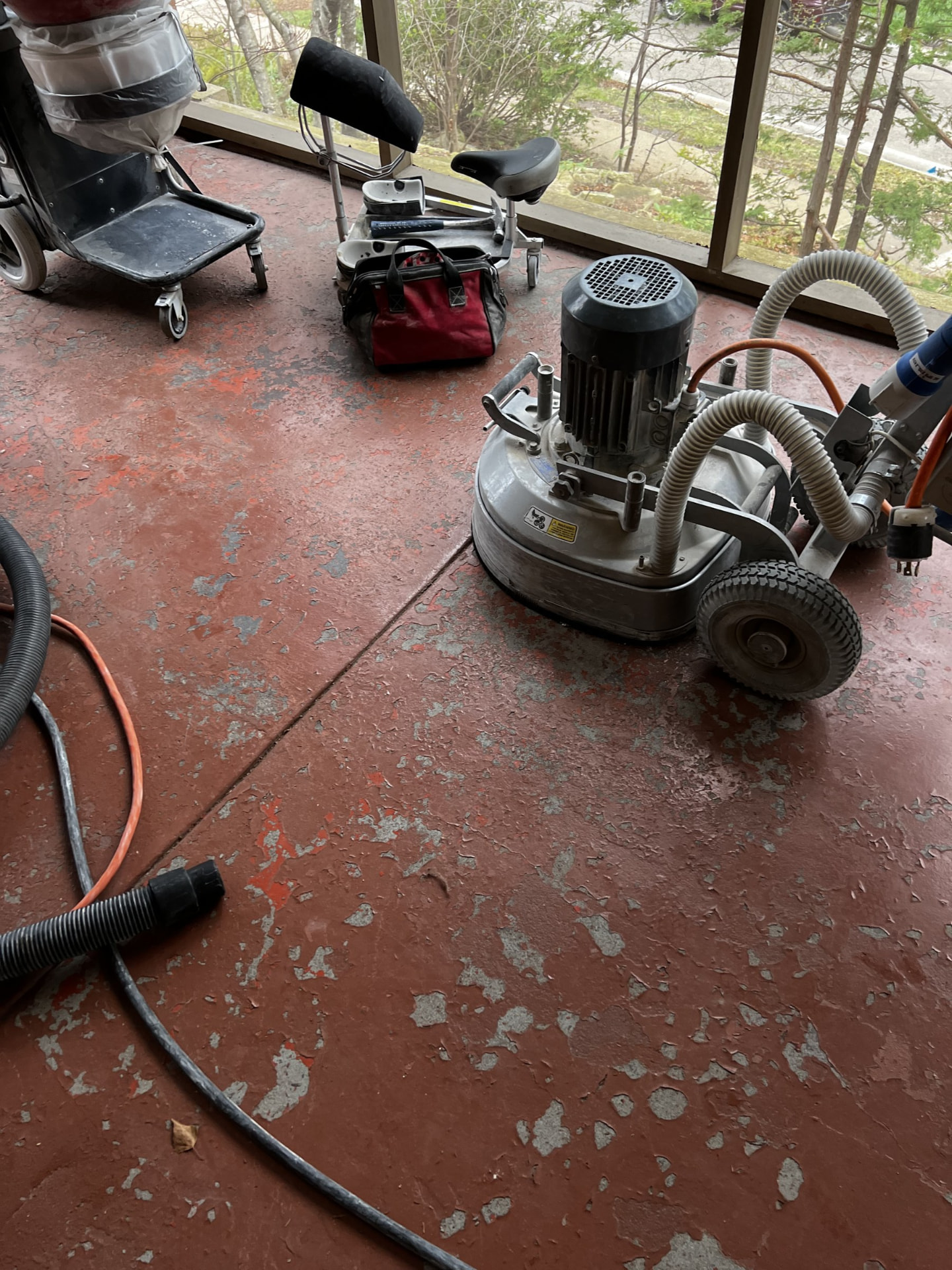 Concrete grinder removing old coating from a patio floor